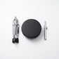 Set of drumming accessories including a black drum pad, two silver drumsticks on a white background